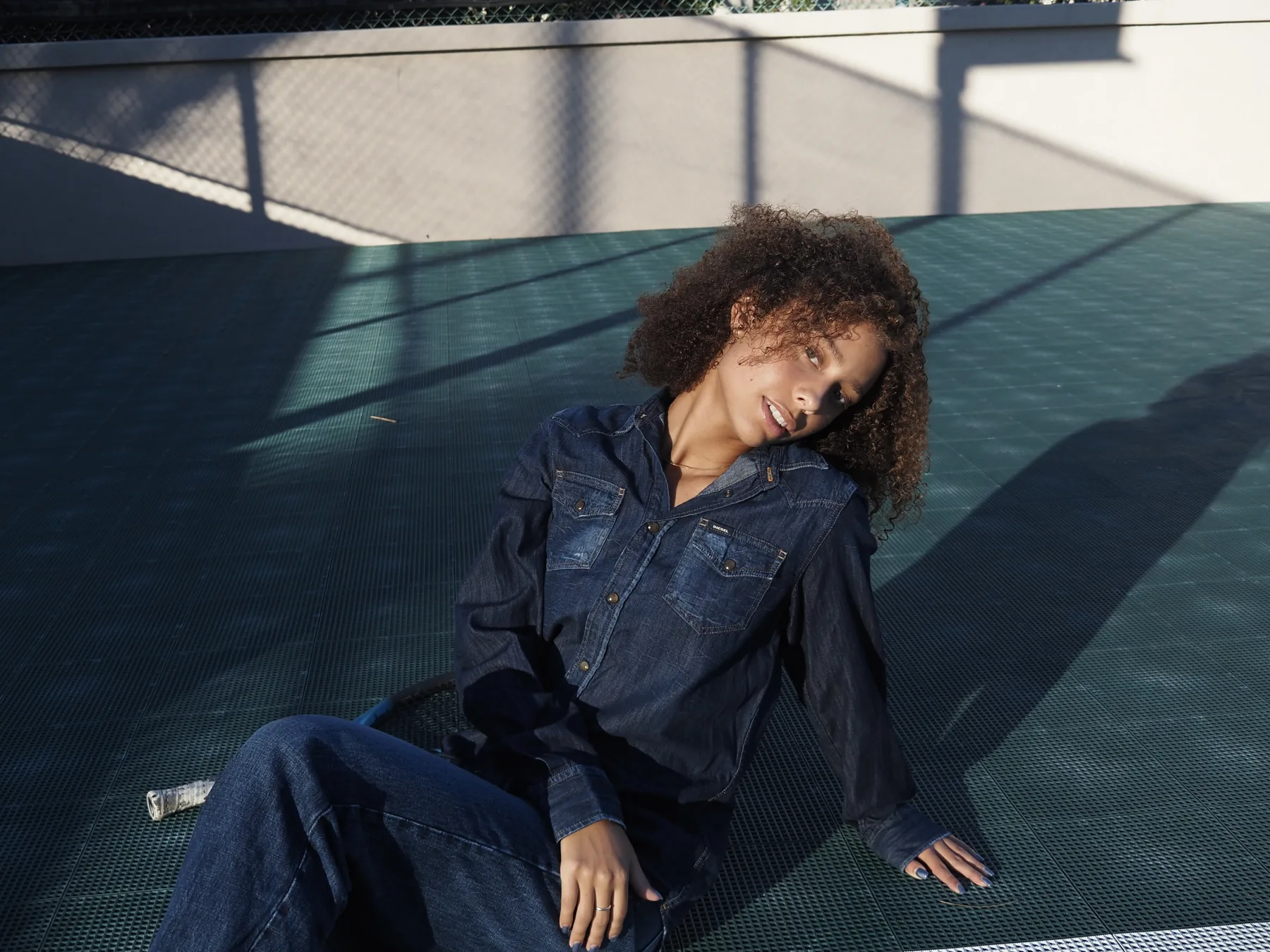 Sophia Coon reclining on a green tennis court in late afternoon light